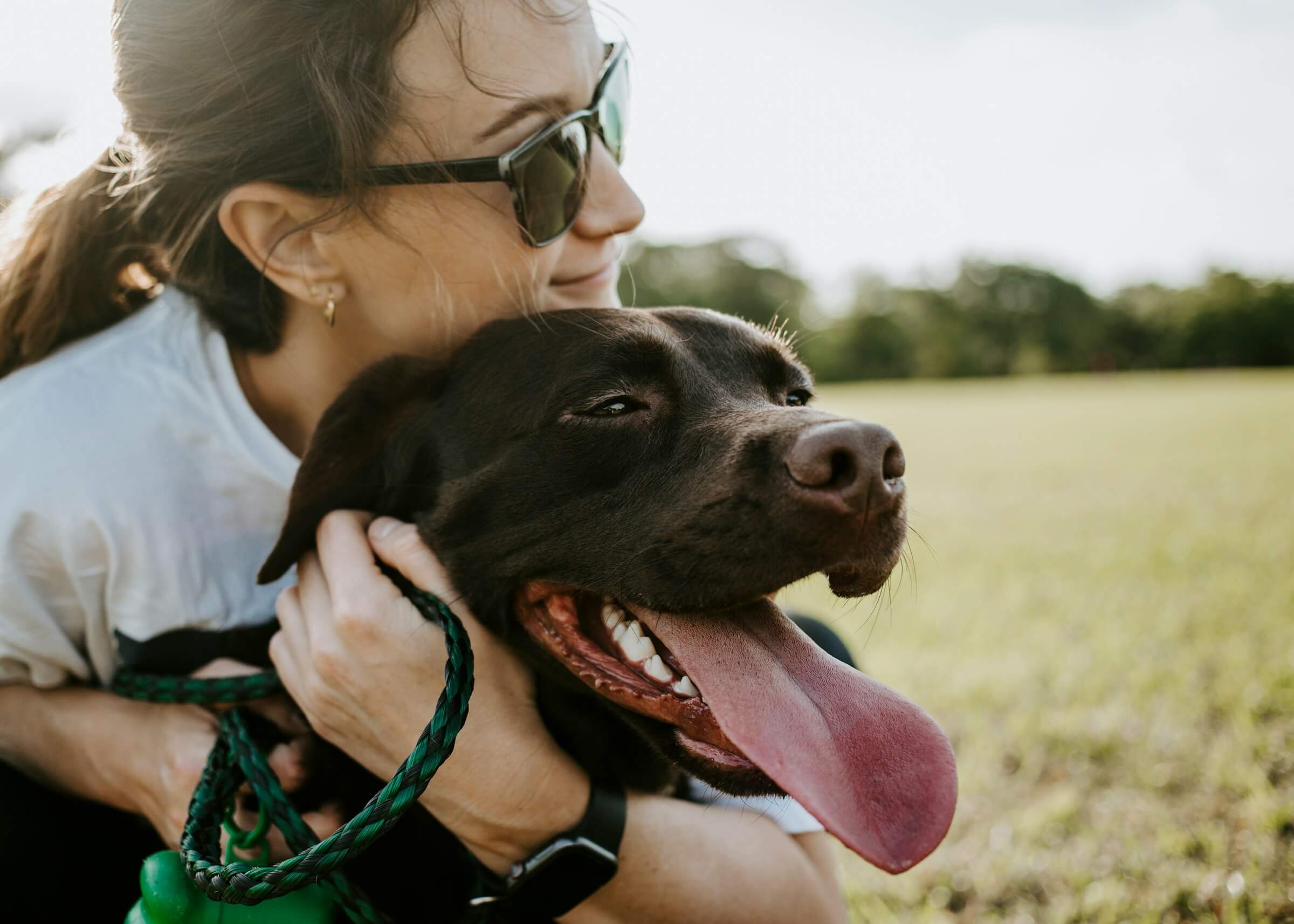 A woman joyfully hugging her dog outdoors