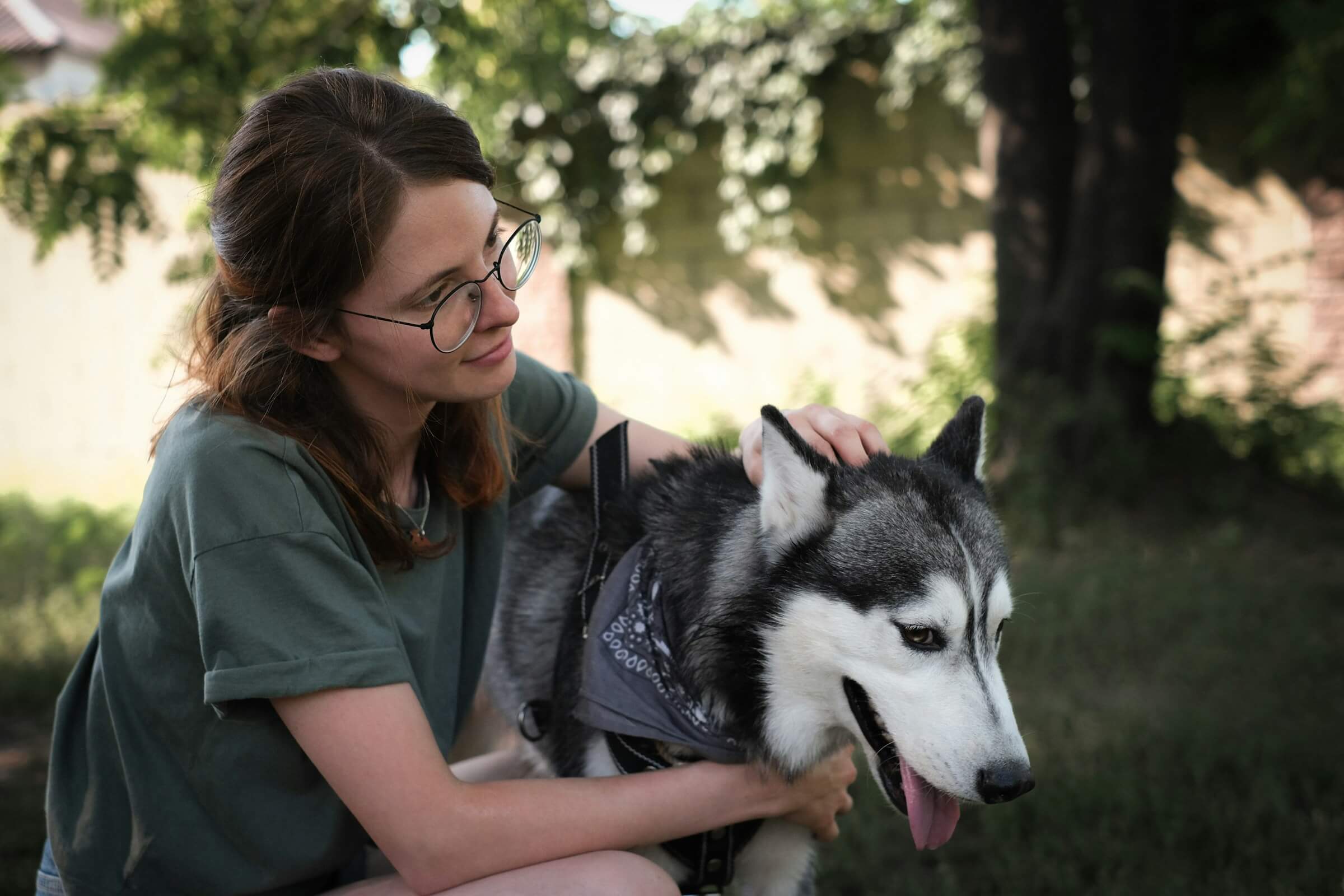 A woman gently caring for a husky wearing a bandana